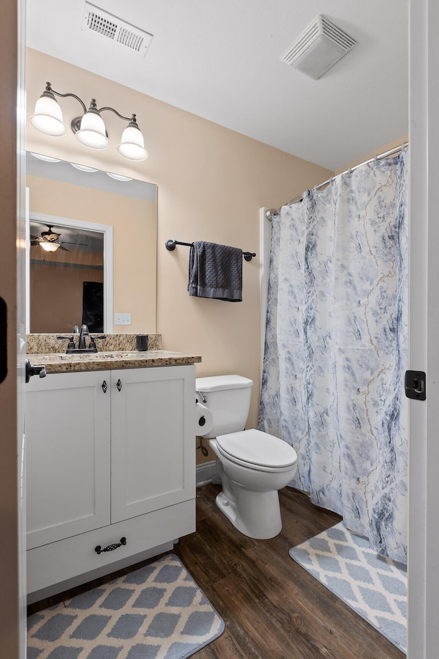 bathroom with wood-type flooring, vanity, curtained shower, toilet, and ceiling fan