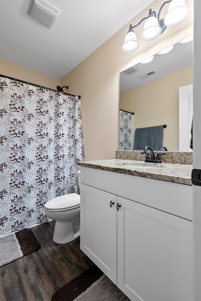 bathroom with toilet, vanity, and hardwood / wood-style floors