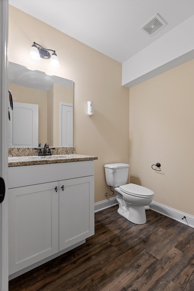 bathroom featuring toilet, vanity, and hardwood / wood-style flooring