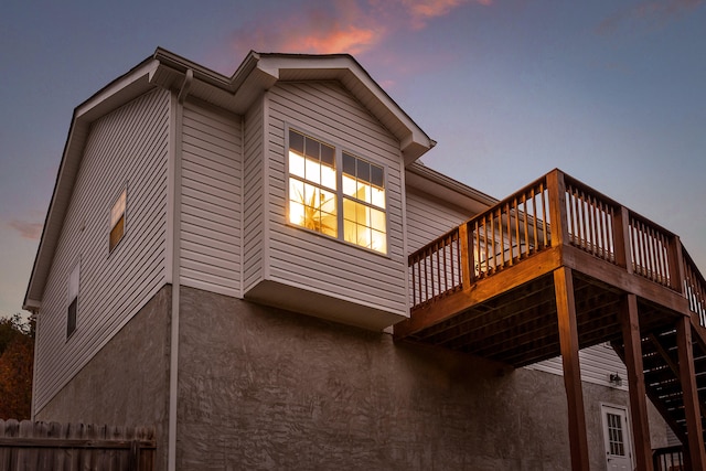 property exterior at dusk featuring a wooden deck