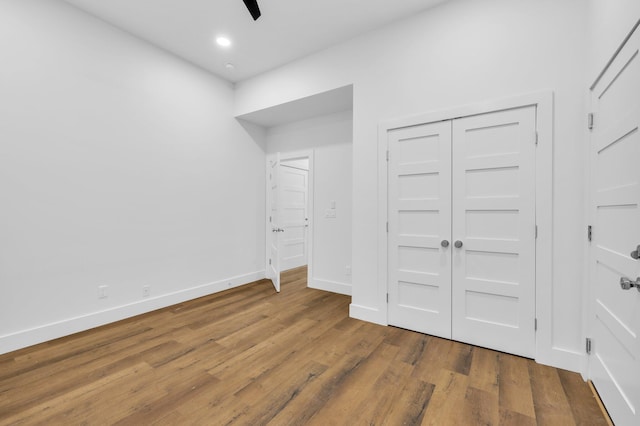 unfurnished bedroom with hardwood / wood-style flooring, ceiling fan, and a closet