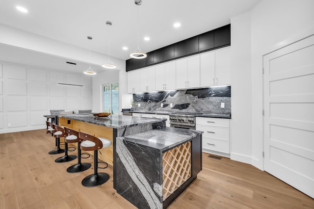 kitchen with pendant lighting, light wood-type flooring, stainless steel range, and a center island