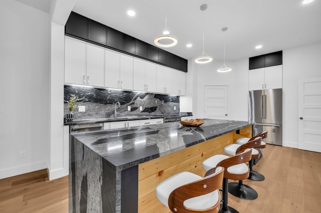 kitchen with a kitchen island, hanging light fixtures, stainless steel fridge, and light hardwood / wood-style flooring