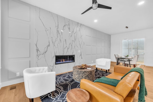 living room with hardwood / wood-style floors, a fireplace, and ceiling fan