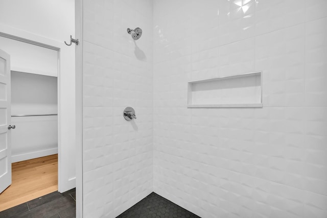 bathroom featuring wood-type flooring and a tile shower