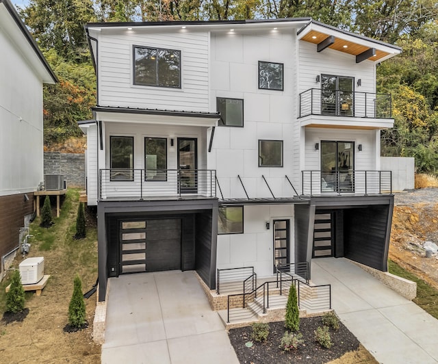 contemporary home with a garage, cooling unit, and a balcony