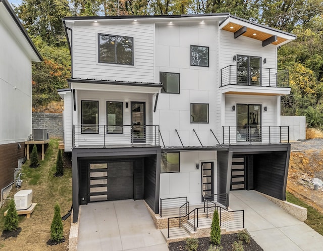 contemporary home with a garage, central AC unit, and a balcony