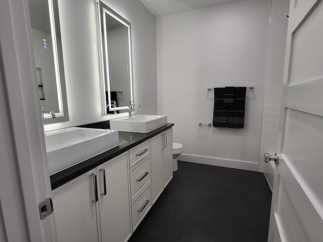 bathroom with toilet, vanity, and tile patterned flooring