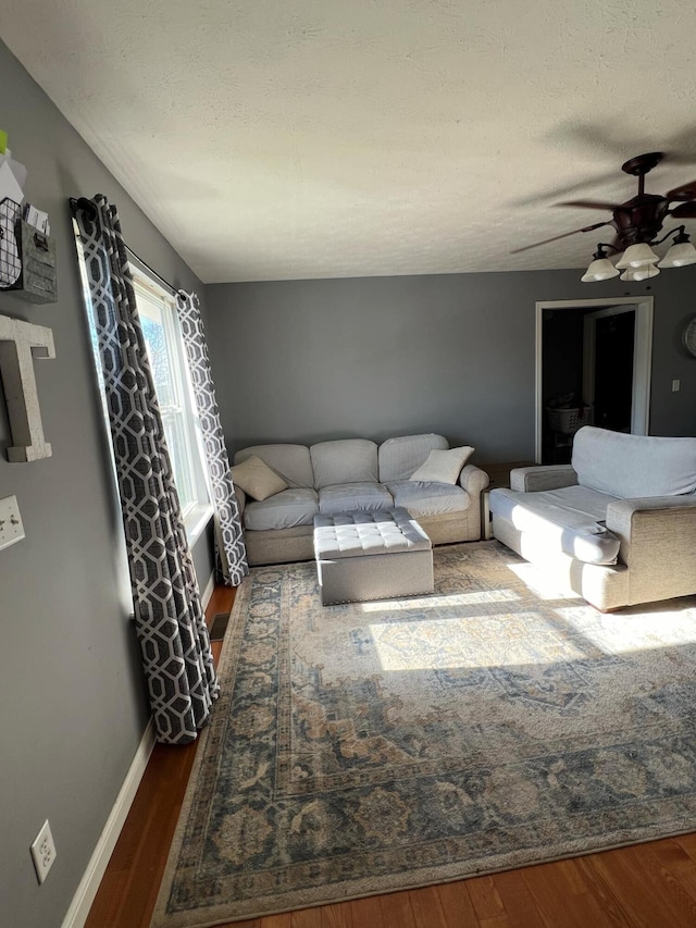 living room featuring ceiling fan, a textured ceiling, and dark hardwood / wood-style flooring