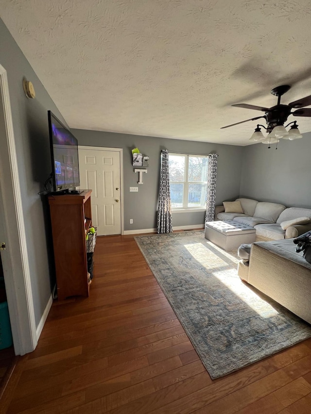 living room featuring dark wood-type flooring, a textured ceiling, and ceiling fan