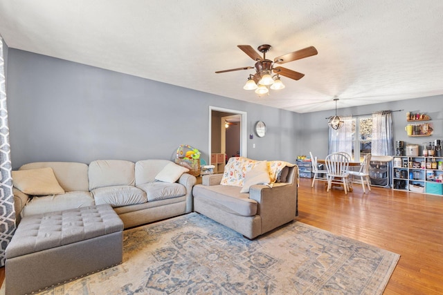 living room with a textured ceiling, wood-type flooring, and ceiling fan