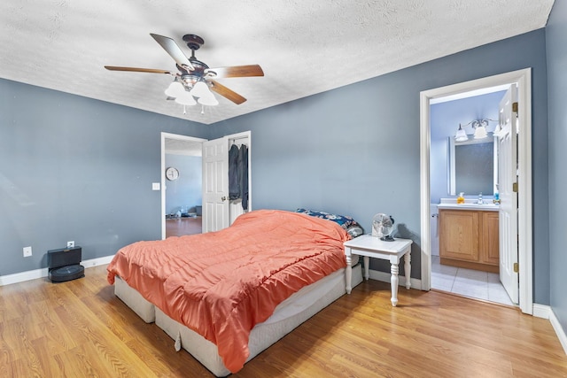 bedroom featuring connected bathroom, a textured ceiling, ceiling fan, and light hardwood / wood-style flooring