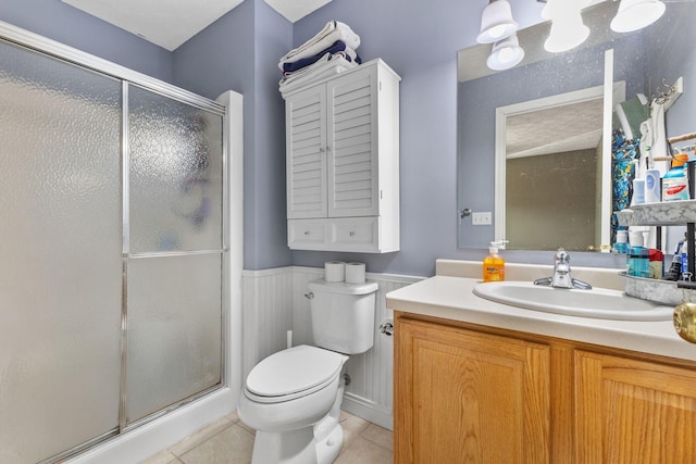 bathroom featuring tile patterned flooring, vanity, a shower with shower door, and toilet