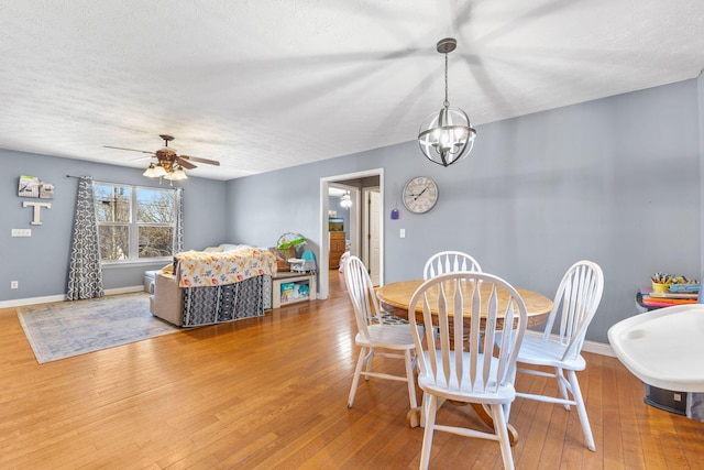 dining area with hardwood / wood-style flooring, ceiling fan with notable chandelier, and a textured ceiling