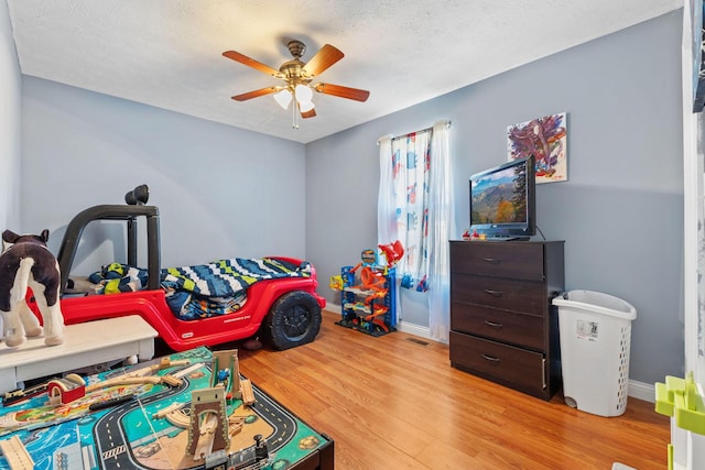 bedroom featuring a textured ceiling, light hardwood / wood-style floors, and ceiling fan