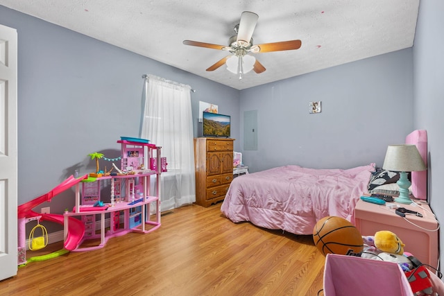 bedroom featuring a textured ceiling, electric panel, ceiling fan, and light wood-type flooring