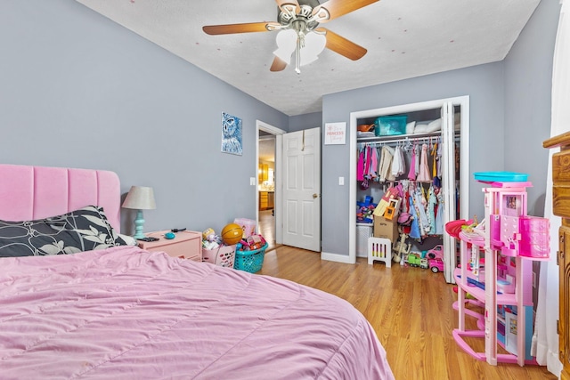 bedroom with light wood-type flooring, ceiling fan, and a closet