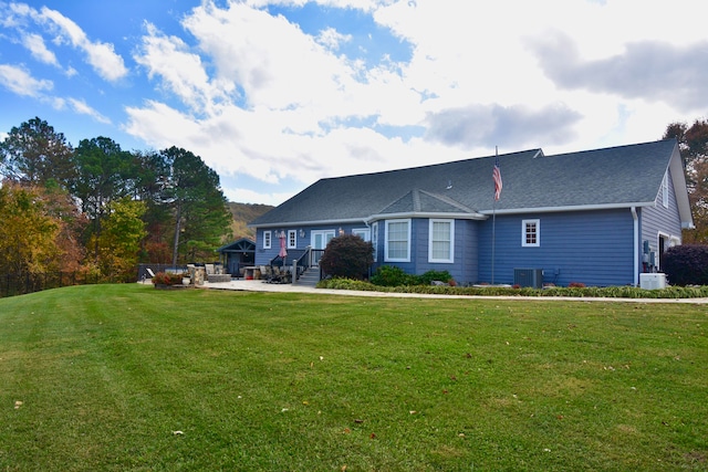 rear view of house with central AC and a lawn