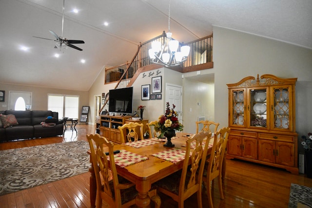 dining area featuring high vaulted ceiling, hardwood / wood-style floors, and ceiling fan with notable chandelier