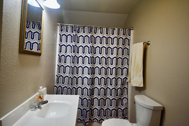 bathroom featuring vaulted ceiling, curtained shower, sink, and toilet