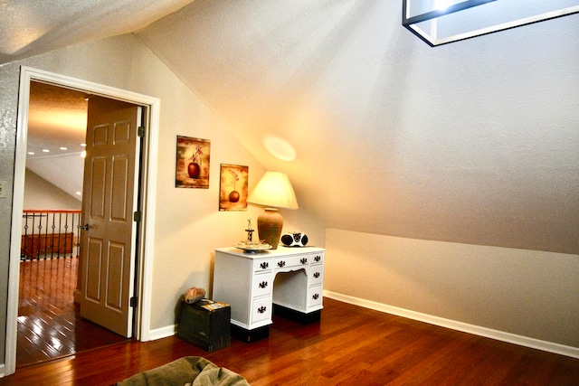 additional living space featuring vaulted ceiling with skylight and dark hardwood / wood-style flooring