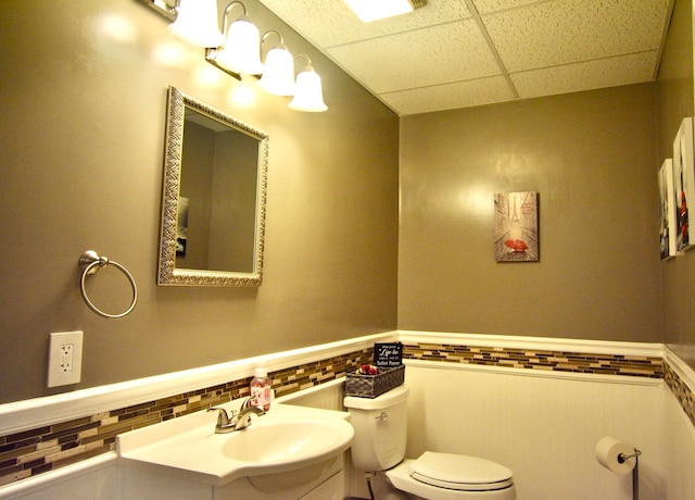 bathroom featuring vanity, toilet, tasteful backsplash, and a drop ceiling