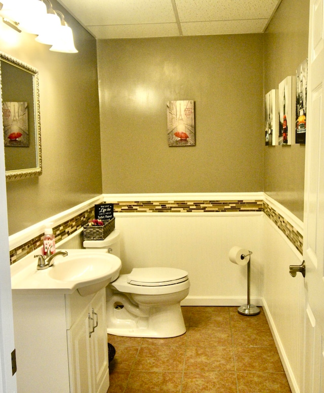 bathroom featuring a drop ceiling, tile patterned flooring, vanity, and toilet