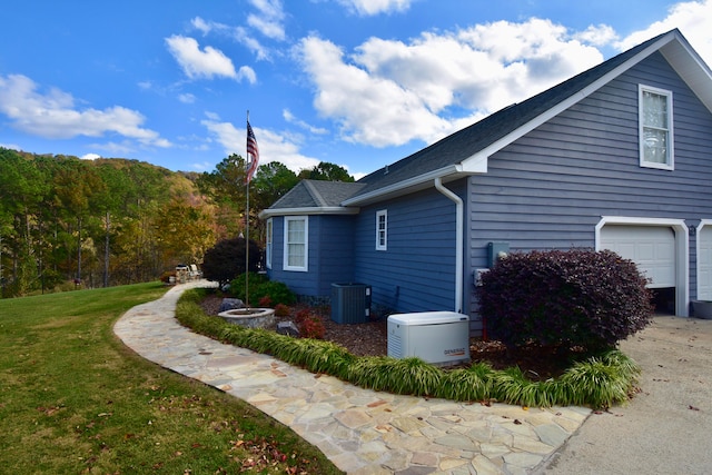 view of home's exterior with a garage, central AC, and a yard