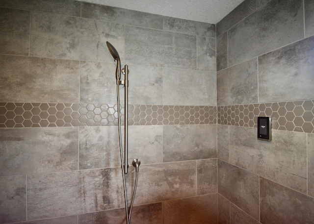 details with a textured ceiling and tiled shower