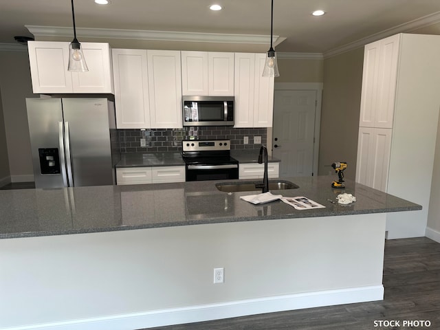 kitchen with stainless steel appliances, sink, dark stone counters, white cabinets, and dark hardwood / wood-style flooring