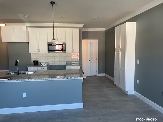 kitchen featuring light stone counters, crown molding, backsplash, sink, and white cabinets