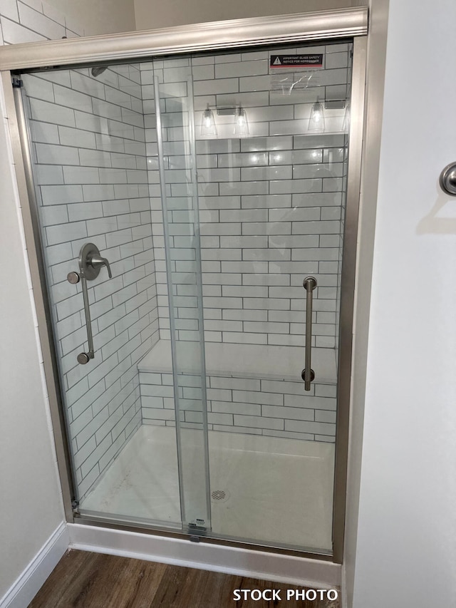 bathroom with hardwood / wood-style flooring and a shower with shower door