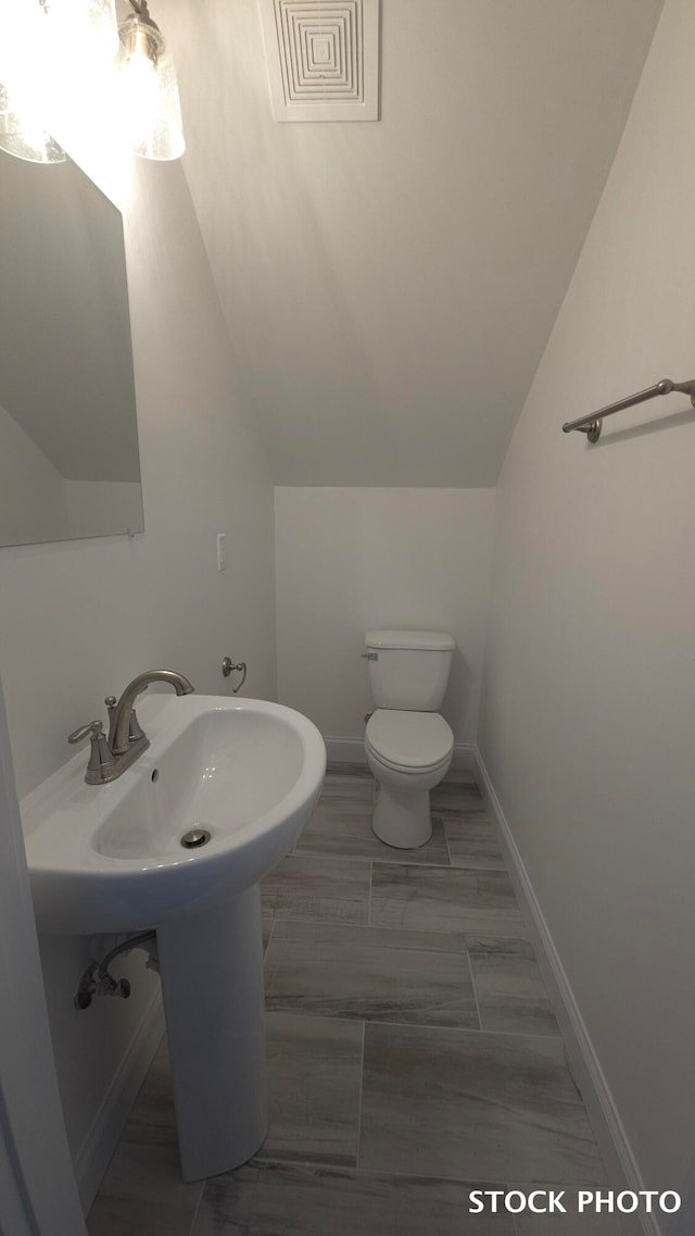 bathroom featuring toilet and vaulted ceiling