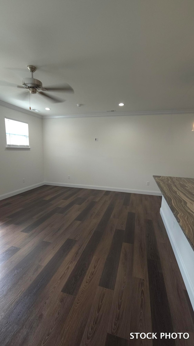 empty room featuring dark hardwood / wood-style floors, crown molding, and ceiling fan