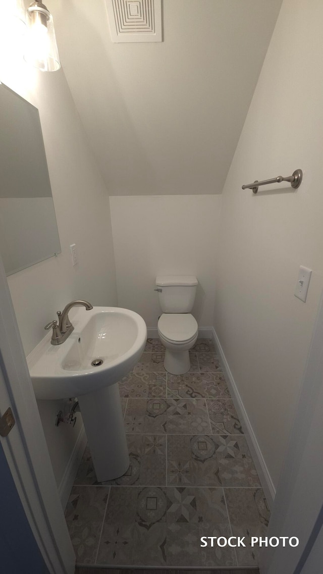 bathroom with toilet, lofted ceiling, and tile patterned floors