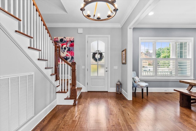 entrance foyer featuring dark hardwood / wood-style floors, an inviting chandelier, and ornamental molding