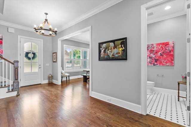 foyer featuring dark hardwood / wood-style floors, crown molding, and a notable chandelier