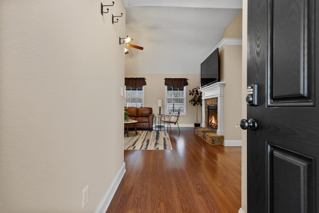 foyer entrance featuring vaulted ceiling, dark wood-type flooring, and a fireplace