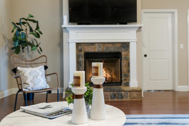 sitting room featuring wood-type flooring and a stone fireplace