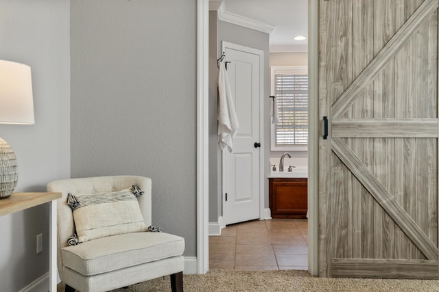 sitting room with ornamental molding, a barn door, and light tile patterned flooring