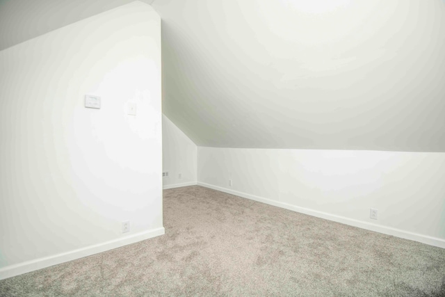 bonus room with light carpet and vaulted ceiling