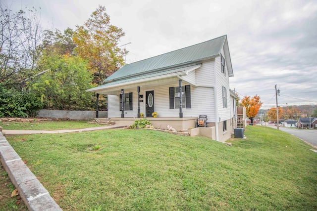 view of front facade featuring cooling unit, a front yard, and covered porch