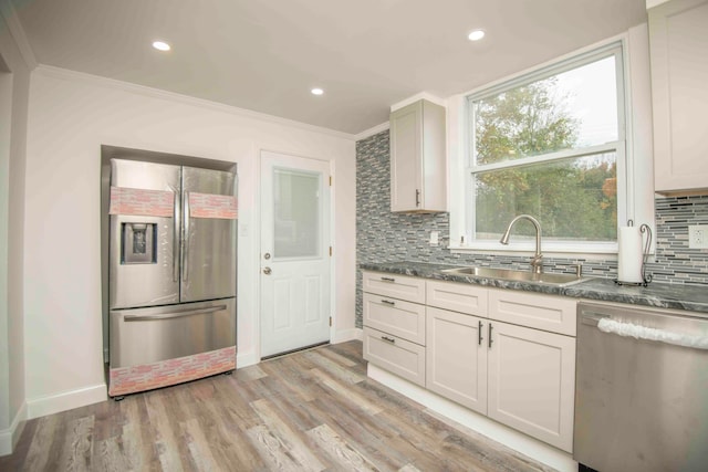 kitchen with crown molding, light wood-type flooring, appliances with stainless steel finishes, backsplash, and sink