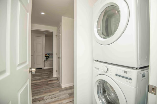 laundry area with stacked washer and clothes dryer and hardwood / wood-style flooring