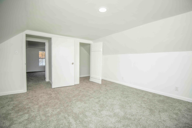 bonus room with light carpet and vaulted ceiling