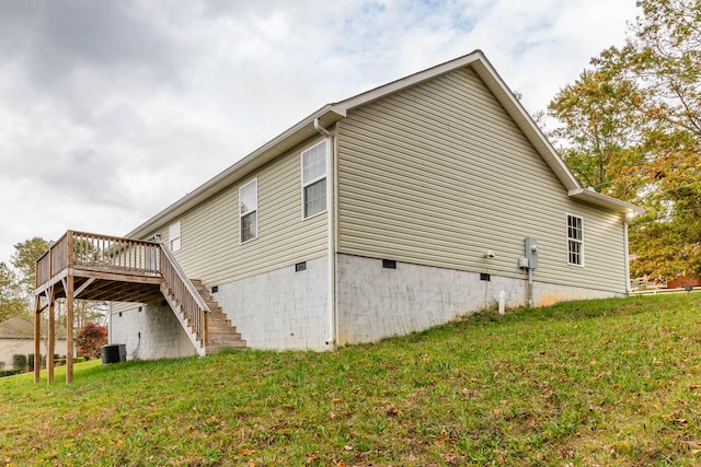 view of home's exterior with a wooden deck, central AC, and a yard