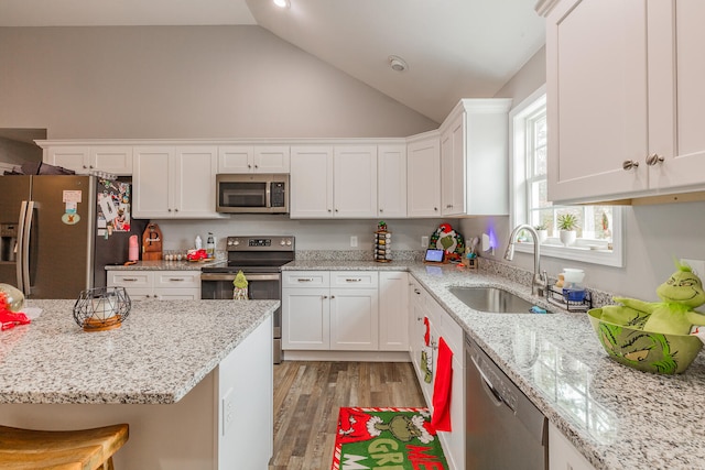 kitchen with sink, appliances with stainless steel finishes, light stone countertops, light hardwood / wood-style flooring, and white cabinets