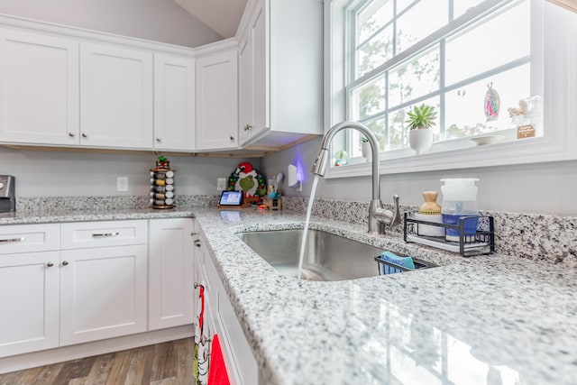 kitchen featuring white cabinetry, light stone counters, and light wood-type flooring