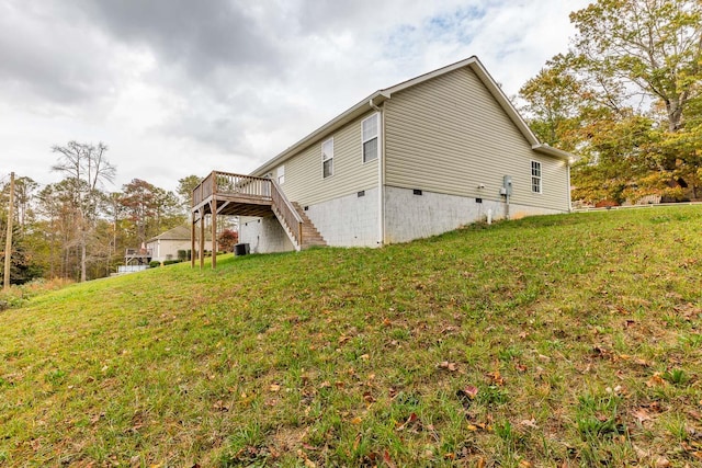 view of home's exterior featuring a deck, a lawn, and central AC unit