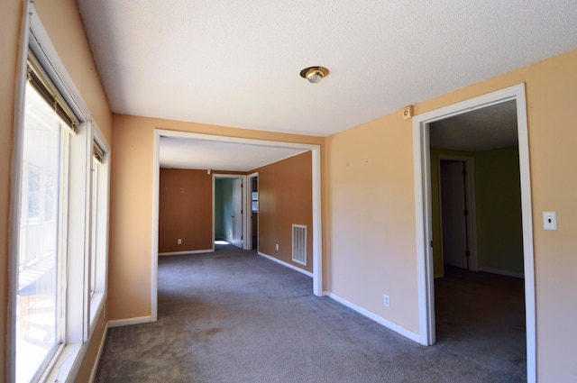 carpeted empty room featuring a textured ceiling